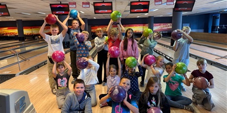 Powiększ grafikę: Grupa dzieci pozuje do zdjęcia z kulami do bowlingu.