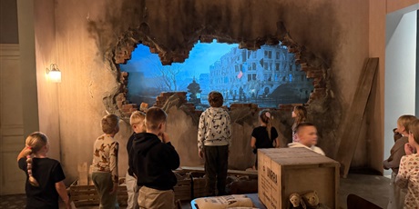 Powiększ grafikę: Grupa dzieci w jednym pomieszczeń muzeum zniszczonych podczas II wojny światowej.