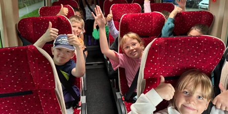 Powiększ grafikę: Uczniowie jadą autobusem na zieloną szkołę, pełni radości i podekscytowania przed wspólną przygodą.