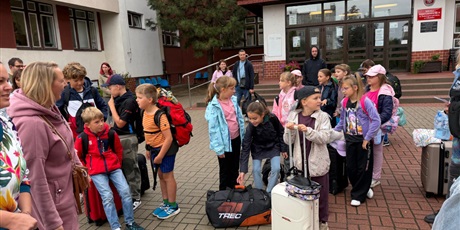Powiększ grafikę: Klasa przed szkołą z walizkami, gotowa do wyjazdu na zieloną szkołę.