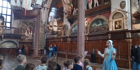 Powiększ grafikę: Panienka z Okienka - przewodniczka oprowadza dzieci po Dworze Artusa w Gdańsku.