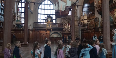 Powiększ grafikę: Panienka z Okienka - przewodniczka oprowadza dzieci po Dworze Artusa w Gdańsku.