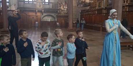 Powiększ grafikę: Panienka z Okienka - przewodniczka oprowadza dzieci po Dworze Artusa w Gdańsku.