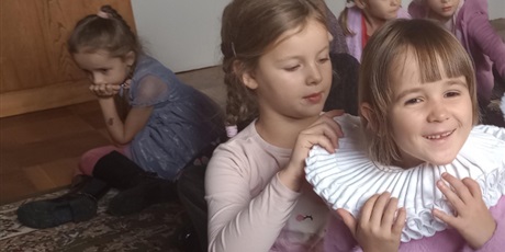 Powiększ grafikę: Dziewczynka pomaga koleżance w zapięciu kołnierza.