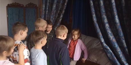 Powiększ grafikę: Dziewczynka próbuje usiąść na łóżku z baldachimem. Śmieje się przy tym. Łóżko jest drewniane i pokryte dużą ilością pościeli.