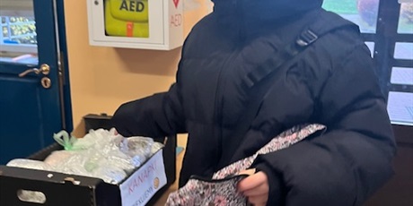 Powiększ grafikę: Uśmiechnięta dziewczynka wkłada kanapkę do pojemnika.