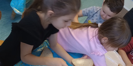 Powiększ grafikę: Dzieci trzymają w ręku posmarowane kromki chleba. Sięgają po inne produkty, aby położyć je na na kanapce.