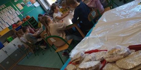 Powiększ grafikę: Na pierwszym tle widać kanapki przygotowane przez dzieci. W tle widzimy dzieci pracujące przy stolikach.