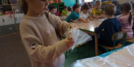 Powiększ grafikę: Dziewczynka nakleja naklejkę z miłym słowem na zapakowaną kanapkę.