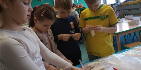 Powiększ grafikę: Dzieci naklejają naklejkę z miłym słowem na zapakowaną kanapkę.