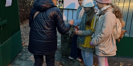 Powiększ grafikę: Troje dzieci - wolontariuszy stoi z puszką, do której zbierają datki. Dzieci ubrane są w żółte koszulki symbolizujące hospicjum. Przy nich stoi osoba wpłacająca.