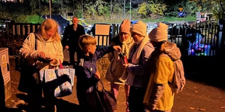 Powiększ grafikę: Troje dzieci - wolontariuszy stoi z puszką, do której zbierają datki. Dzieci ubrane są w żółte koszulki symbolizujące hospicjum. Przy nich stoi osoba wpłacająca.