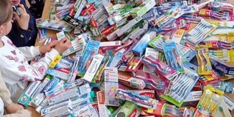 Powiększ grafikę: Na zdjęciu znajdują się dzieci, które segregują dużą ilość artykułów higienicznych zebranych podczas akcji KUP PAN SZCZOTKĘ.