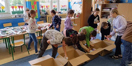 Powiększ grafikę:  Grupa dzieci pakuje do kartonów artykuły higieniczne zebrane podczas akcji KUP PAN SZCZOTKĘ.