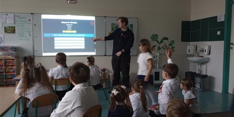 Powiększ grafikę: Pan opowiada dzieciom i pokazuje prezentację multimedialną. Dzieci słuchają i dopytują prowadzącą.