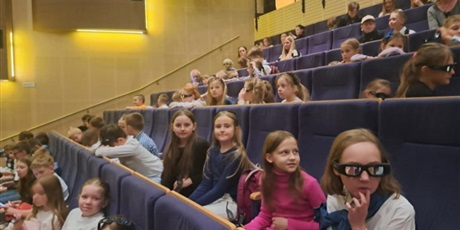 Powiększ grafikę:  Grupa dzieci z klasy  1E i 3D siedzi na fotelach w teatrze.