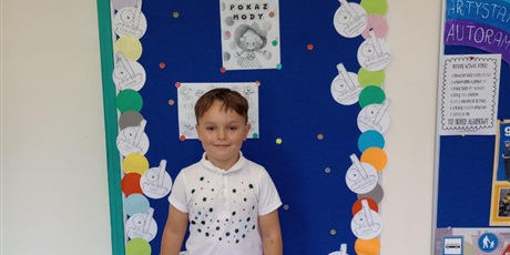 Powiększ grafikę: Chłopiec prezentuje swoje ubranie z akcentem kropki.