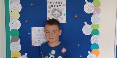 Powiększ grafikę: Chłopiec prezentuje swoje ubranie z akcentem kropki.