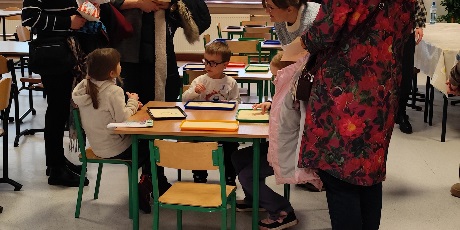 Powiększ grafikę: Przyszli uczniowie szkoły odwiedzają wraz z rodzicami stołówkę szkolną, rysują tam w kaszy, a rodzice uzyskują wyczerpujące odpowiedzi na pytania związane z funkcjonowaniem szkoły. 