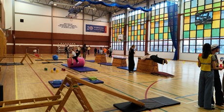 Powiększ grafikę: Przyszli uczniowie naszej szkoły okonują tor przeszkód na szkolnej sali gimnastycznej, rodzice rozmawiają z nauczycielami.