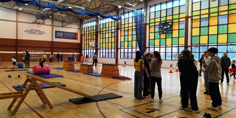 Powiększ grafikę: Przyszli uczniowie naszej szkoły okonują tor przeszkód na szkolnej sali gimnastycznej, rodzice rozmawiają z nauczycielami. 