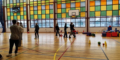 Powiększ grafikę: Przyszli uczniowie naszej szkoły okonują tor przeszkód na szkolnej sali gimnastycznej, rodzice rozmawiają z nauczycielami. 