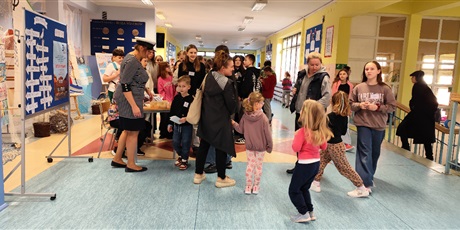 Powiększ grafikę: Przyszli uczniowie szkoły wraz z rodzicami są witani przy wejściu do szkoły. Opiekę nad nimi przejmują szkolni wolontariusze. Gosćie otrzymują mapę podróży i zaczynają zbierać morskie naklejki.