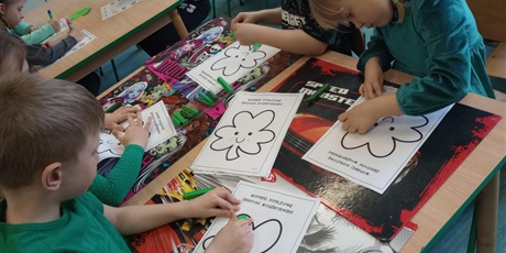 Powiększ grafikę: Dzieci przyklejają do kartki zieloną plastelinę i tworzą zieloną koniczynkę.