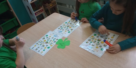 Powiększ grafikę: Dzieci liczą obiekty, które znajdują się na kartkach.