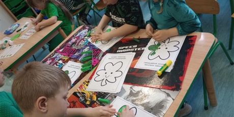 Powiększ grafikę: Dzieci wyklejają zielona bibułą kształt czterolistnej koniczynki.