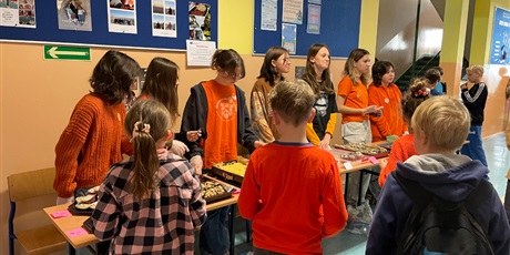 Powiększ grafikę: Uczniowie klasy 6 B sprzedają wypieki na korytarzu szkolnym. Mają założone rękawiczki, dbają o higienę podczas pracy.