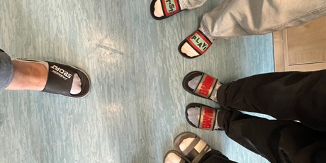 Powiększ grafikę: Stopy w klapkach. Uczniowie prezentują swoje klapki.