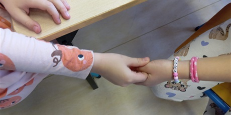 Powiększ grafikę: Dwie koleżanki trzymają się za dłonie.