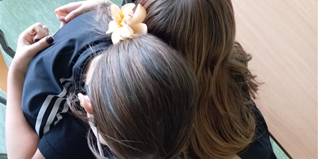 Powiększ grafikę: Dwie koleżanki przytulają się.