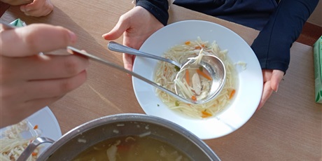 Powiększ grafikę: Koleżanka nalewa drugiej koleżance chochelką zupę z wazy.