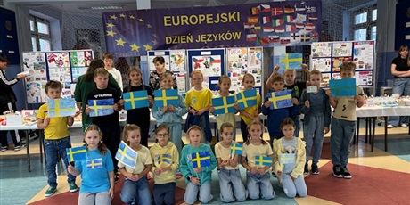 Powiększ grafikę: Dzieci z flagami Szwecji - Grupa małych dzieci ustawiona do zdjęcia na holu szkoły z flagami Szwecji w dłoniach.