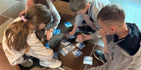 Powiększ grafikę: Grupa dzieci układa puzzle.