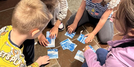 Powiększ grafikę: Grupa czwórki dzieci układa puzzle.