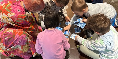 Powiększ grafikę: Grupa dzieci z pomocą pani przewodnik układa puzzle.