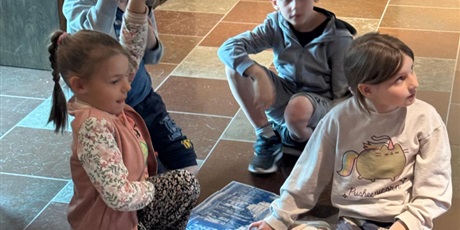 Powiększ grafikę: Grupa dzieci ułożyła puzzle. chłopiec i dziewczynka trzymają podniesione ręce do góry.