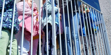 Powiększ grafikę: Dzieci i nauczycielka stoją na schodach zewnętrznych. Uśmiechają się