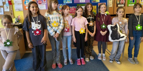 Powiększ grafikę: Grupa dziewczynek pozuje do zdjęcia.   Za nimi stoi granatowa tablica z kolorową dekoracją i napisem I Edycja Konkursu Recytatorskiego „W kręgu poezji Ludwika Jerzego Kerna”.