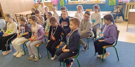 Powiększ grafikę: Grupa dzieci siedzi na krzesełkach w świetlicy.