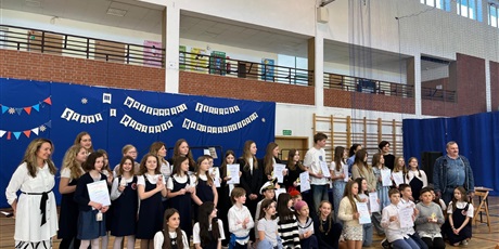 Powiększ grafikę: Grupa dzieci w wieku od 7 do 15 lat. Uśmiechają się. W tle dekoracja z napisem: III wojewódzki festiwal szant i piosenek marynistycznych.