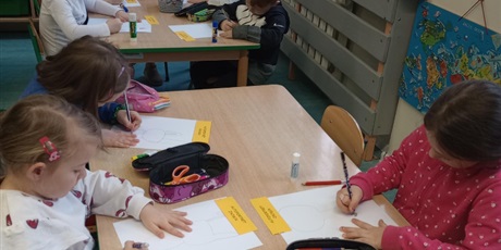 Powiększ grafikę: Grupa dzieci w wieku 7 lat pracuje przy stolikach. Dzieci wykonują autoportret zająca.