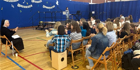 Powiększ grafikę: Publiczność porusza się w rytm śpiewu podczas IV Wojewódzkiego Konkursu Piosenki Religijnej w sali gimnastycznej.