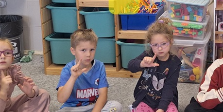 Powiększ grafikę: Dzieci siedzą na dywanie i układają z paluszków literę l.