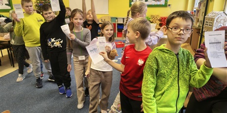 Powiększ grafikę: Grupa dzieci pozuje do zdjęcia. W rękach trzymają kartkę z rozwiązaną świąteczną krzyżówką.