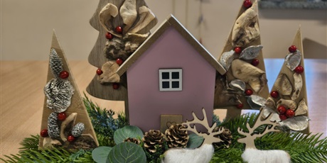 Powiększ grafikę: Na stole znajduje się ręcznie wykonana dekoracja świąteczna- choinki, domek, dwa jelenie.
