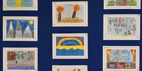 Powiększ grafikę: Granatowa tablica ścienna, na której znajdją się kolorowe projekty znaczków pocztowych. Na górze znajduje się napis: PROJEKT ZNACZKA POCZTOWEGO.